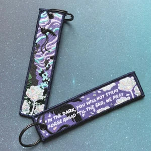 Two purple embroidered keychains with Ultima Thule designs on a gray surface